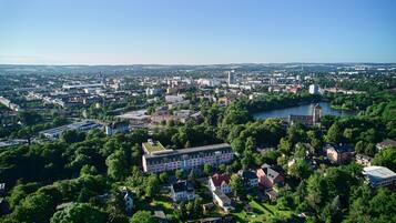 An aerial view of a city with a prominent building complex surrounded by greenery and a river.