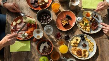 Una mesa de madera con diversos productos para el desayuno, incluyendo platos de comida, un hervidor y una taza de café.