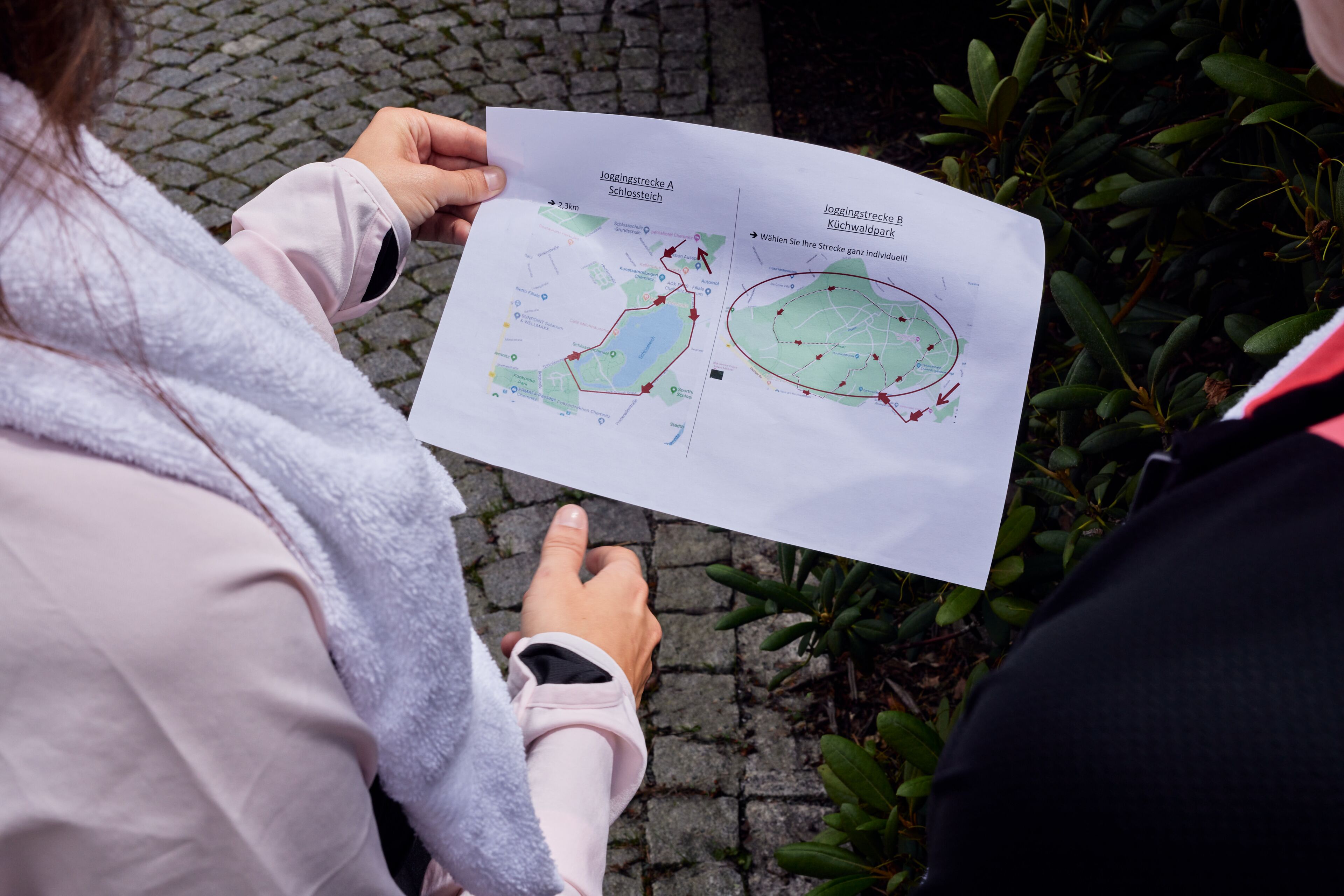A person holding a map with marked jogging routes.