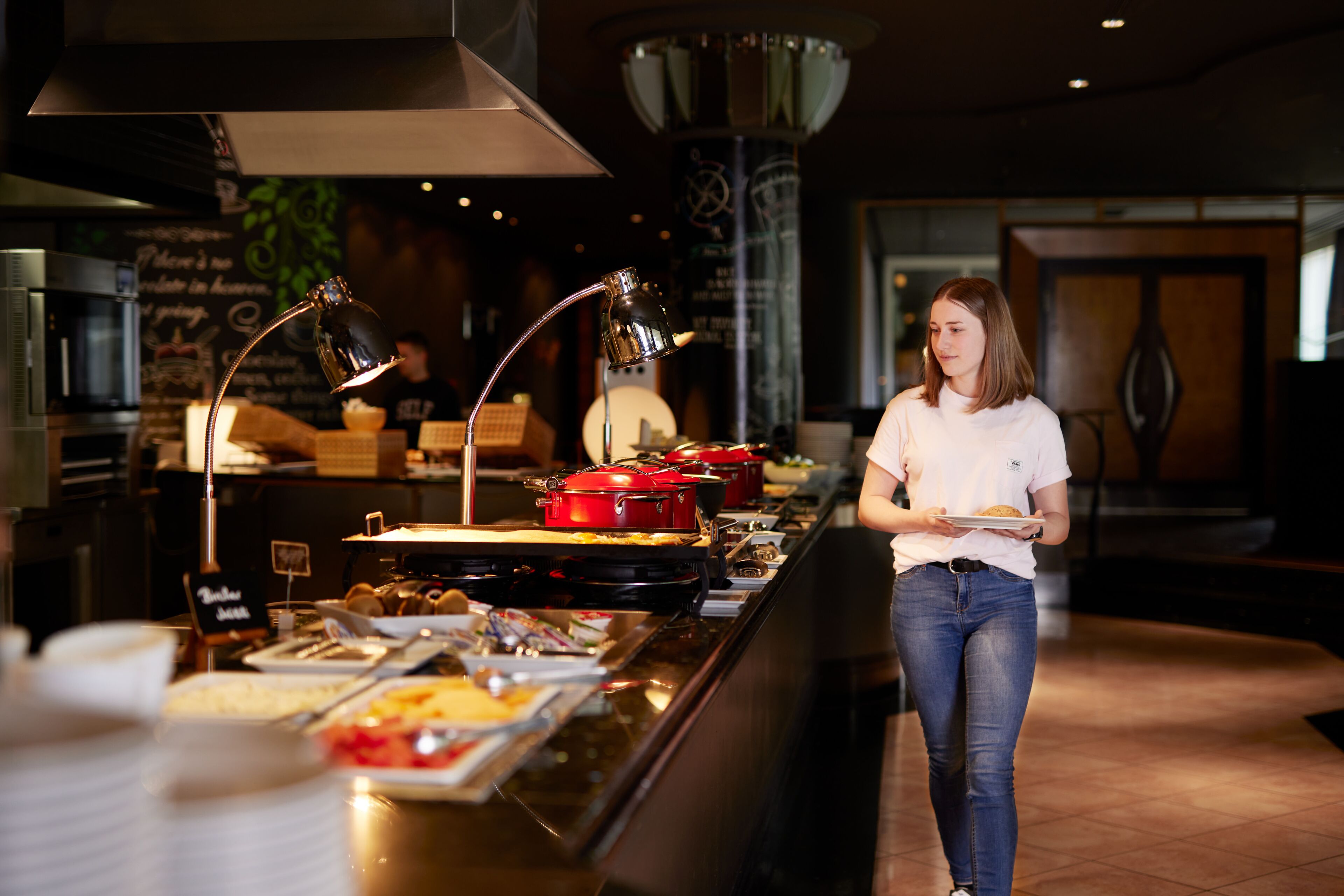 Zona de buffet con diferentes alimentos y una persona atendiendo.