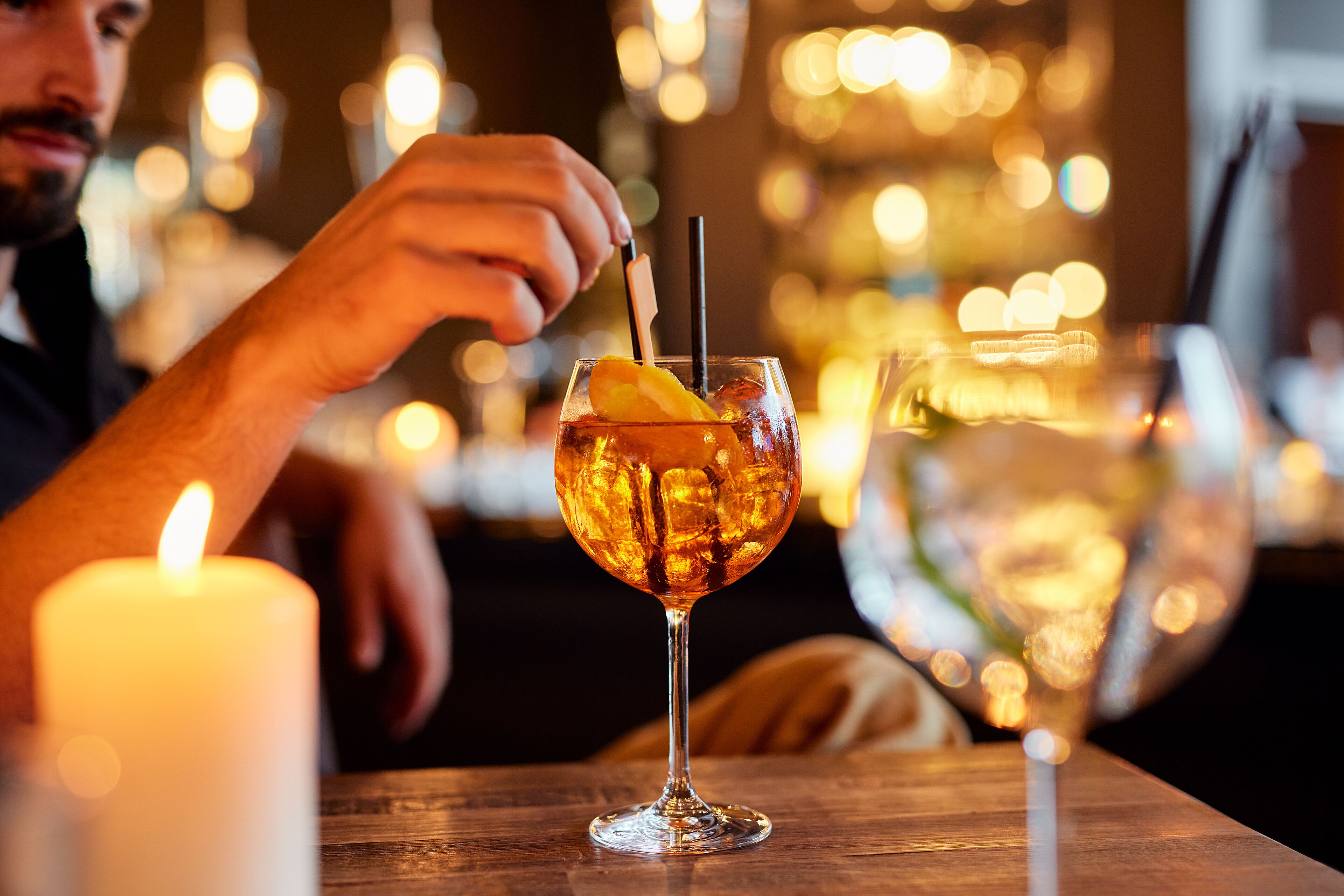 Eine Kerze auf einem Tisch, dazu ein Glas Eistee und eine Orangenscheibe.