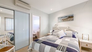 Una camera da letto con un letto grande, un comodino, una sedia, una finestra e un quadro appeso al muro.
