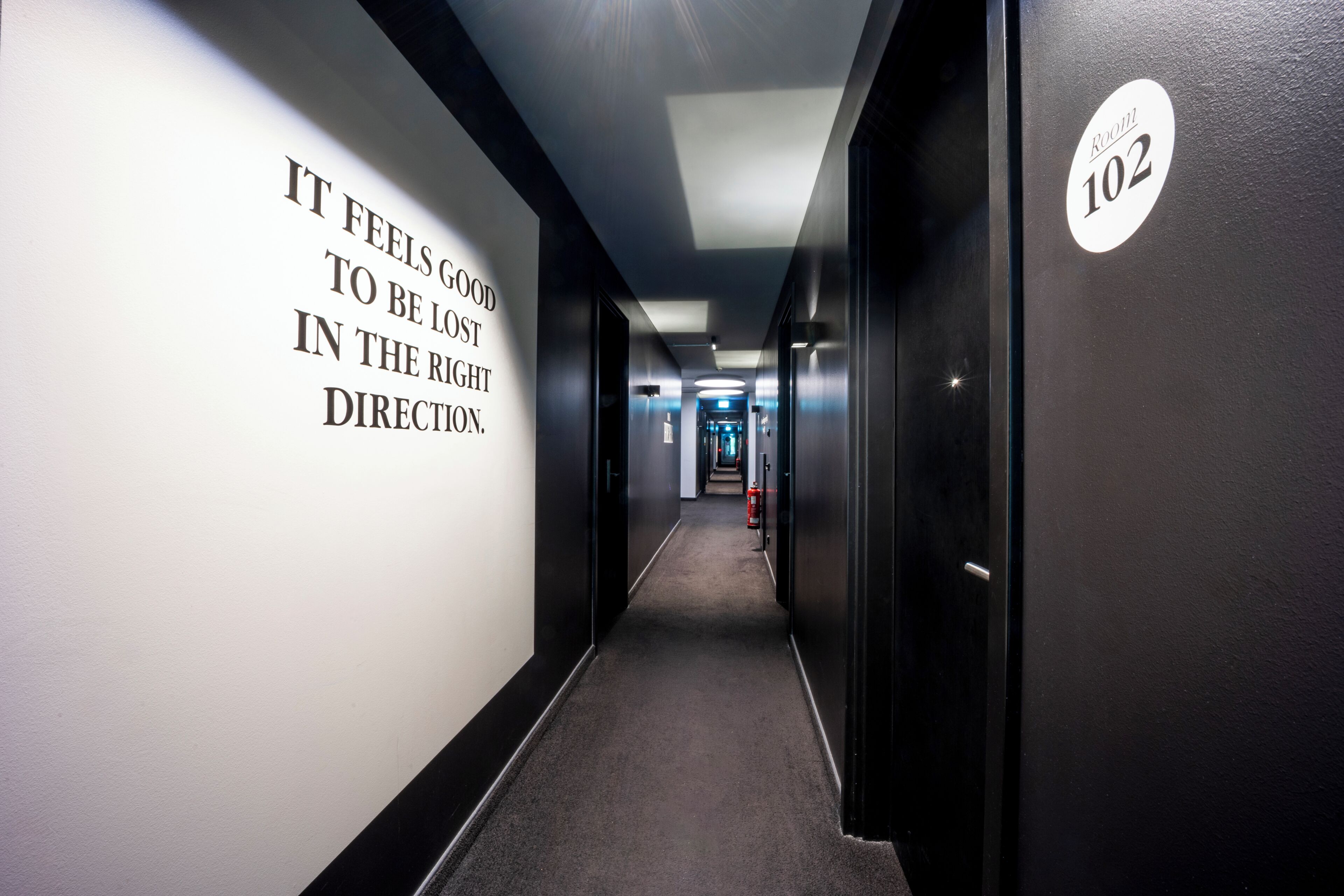 Un pasillo con un letrero en la pared que dice 'Se siente bien estar perdido en la dirección correcta'.