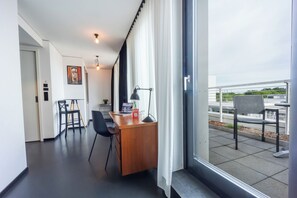 A modern hotel room with a wooden desk, a chair, a laptop, and a window with curtains. - Brera Serviced Apartments Schwabing (Munich)