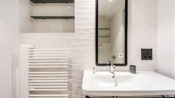 Un baño moderno con un lavamanos blanco, un espejo y un perchero para toallas.