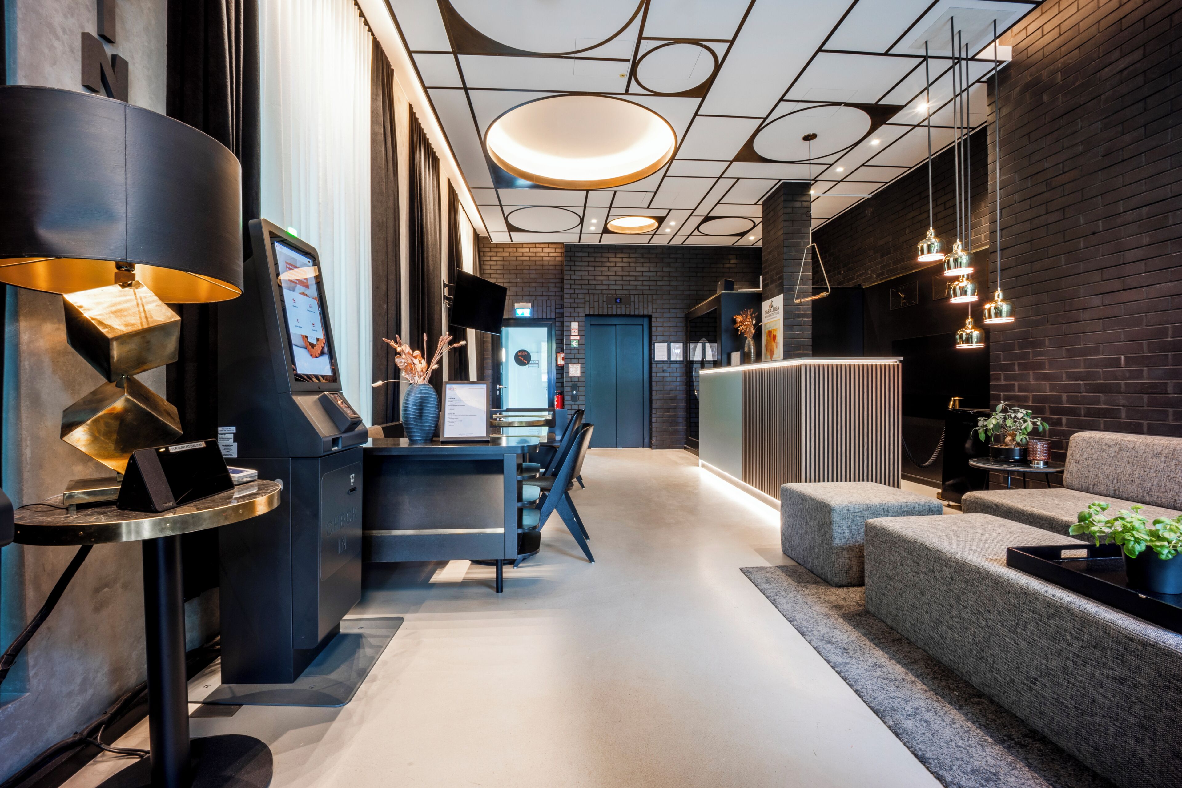 Een modern interieur met een receptiebalie, incheckruimte, zitplaatsen en een bakstenen muur.