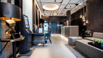 A modern interior with a reception desk, check-in area, seating, and a brick wall.
