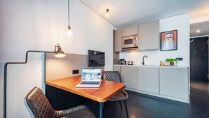 A modern kitchen with a microwave, a sink, and a dining area with a laptop on the table. - Brera Serviced Apartments Schwabing (Munich)
