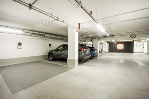 A parking garage with multiple parking spaces, a fire extinguisher, and directional arrows on the floor. - Brera Serviced Apartments Schwabing (Munich)
