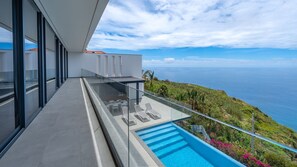 Un balcon moderne avec piscine, offrant une vue sur un paysage côtier.