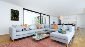 A modern living room with a grey sectional sofa, a glass coffee table, and a red rug.