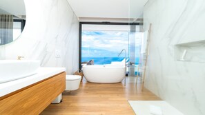 Une salle de bain moderne dotée d’une grande baignoire, d’une douche séparée et offrant une vue sur l’océan.