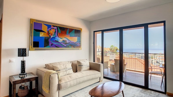 A living room with a beige sofa, a coffee table, and a painting on the wall.