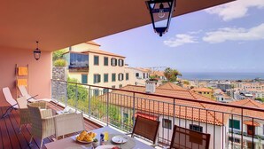 Un balcon avec une table préparée pour le petit-déjeuner, offrant une vue sur le paysage urbain de la côte.