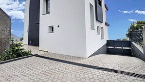 Un bâtiment moderne à la façade blanche, doté de nombreuses fenêtres et d’une entrée sécurisée par un portail.