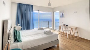 Une chambre d’hôtel moderne avec un grand lit, un bureau et une vue sur l’océan.