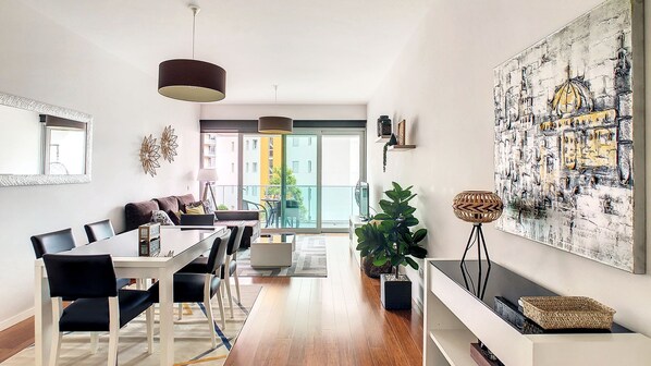 Un salon moderne avec un coin repas, de grandes fenêtres et une vue sur la ville.