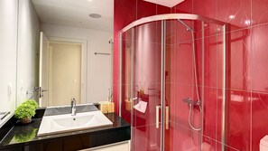 A modern bathroom with a glass shower enclosure, a black countertop sink, and a mirror.