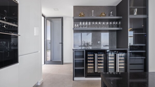A modern kitchen with built-in appliances, a wine rack, and a view to the outside.