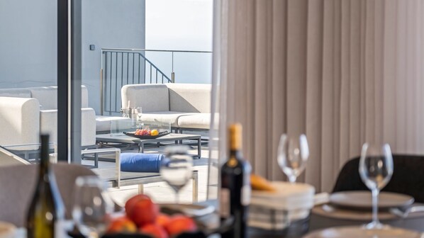 Una sala de estar moderna con un balcón, un comedor con una mesa preparada para dos personas y vista al balcón.