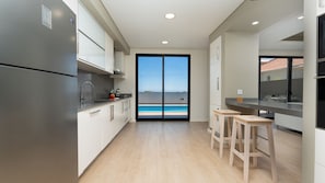 A modern kitchen with a large sliding glass door leading to a pool. - Evoque Villa by LovelyStay (Arco Da Calheta)
