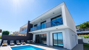 A modern two-story house with a swimming pool, outdoor seating, and a balcony. - Evoque Villa by LovelyStay (Arco Da Calheta)