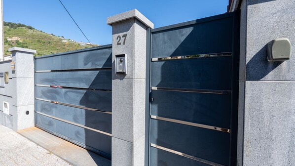 A gated entrance with a number plaque, a metal gate, and a stone wall.