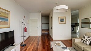 Una sala moderna con un televisor de pantalla plana, una lámpara de pie y un sofá.