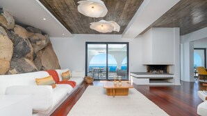 A modern living room with a white sofa, a fireplace, and a view of the sea. - Unmei Villa by LovelyStay (Caniço)