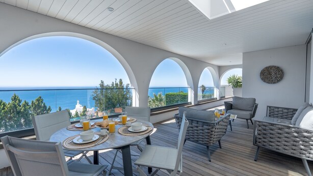 A terrace with a table set for breakfast, overlooking a coastal view. - Unmei Villa by LovelyStay (Caniço)