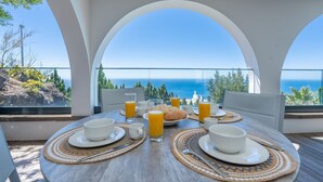 A table set for breakfast with a view of the sea, white arches, and a clear sky. - Unmei Villa by LovelyStay (Caniço)