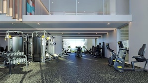 A modern gym with various exercise equipment, a mezzanine level, and large windows.