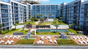 A modern hotel with multiple floors, a central pool, and outdoor seating areas.