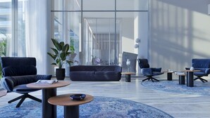 Un vestíbulo amplio con diseño moderno, que cuenta con una zona de estar grande con sofás y sillones, una mesa de centro y una planta en maceta.