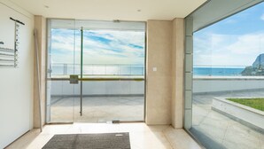 A modern hotel entrance with a glass door leading to a balcony with a view of the sea and a mountain. - Over the Cliff Apartment by LovelyStay (Funchal)