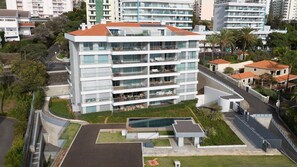 A multi-story hotel with balconies, a swimming pool, and a landscaped garden.
