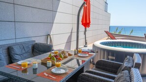 A dining area with a table set for breakfast, a hot tub, and outdoor seating. - Over the Cliff Apartment by LovelyStay (Funchal)