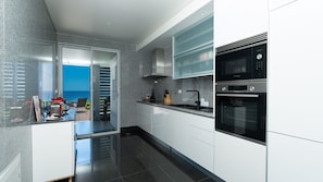 A modern kitchen with a view of the sea, a red toaster, and a Bosch oven.