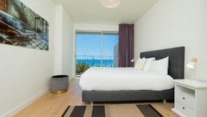 A modern bedroom with a large bed, a nightstand, a lamp, a trash can, and a view of the sea. - Over the Cliff Apartment by LovelyStay (Funchal)