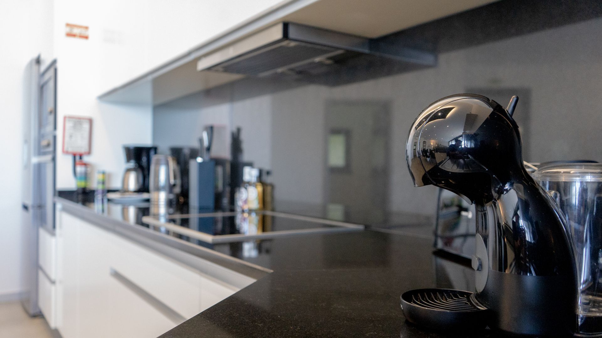 A modern kitchen with a black countertop, a coffee machine, and a blender.