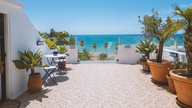 A terrace with a view of the sea, potted plants, and a table with chairs. - Fisherman's cottage a few steps from the beach (Olhos de Água)