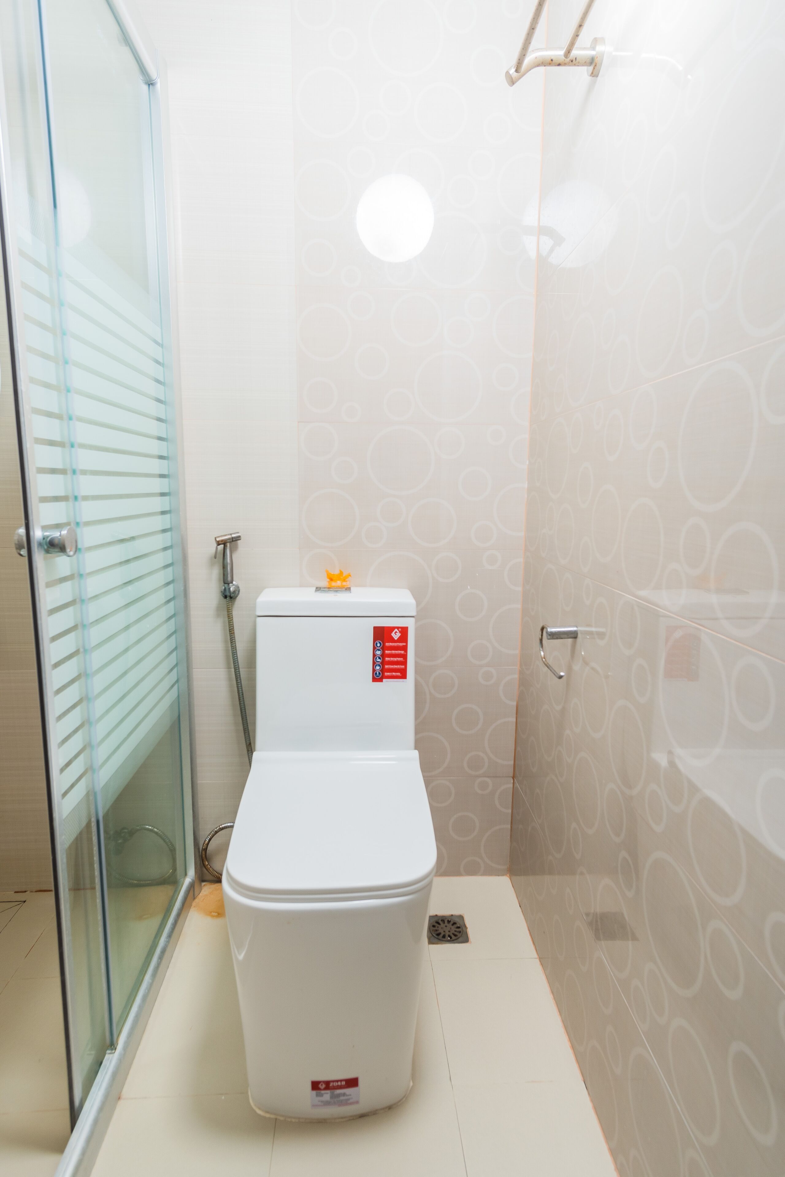 A modern bathroom with a glass shower enclosure, a white toilet, and patterned wall tiles.