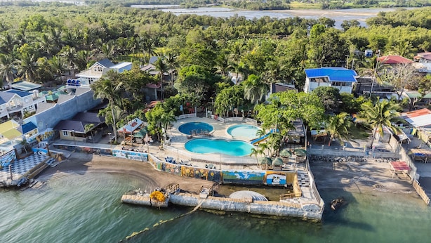 An aerial view of a resort with multiple swimming pools, palm trees, and a beach area. - Villa Elizabeth Beach Resort (Lucena)