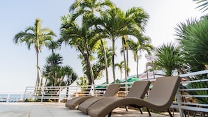 A beachside lounge area with wicker lounge chairs and a white railing. - Villa Elizabeth Beach Resort (Lucena)