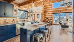 A spacious kitchen with a large island, wooden ceiling, and a view of snowy mountains through large windows. - Lake Front! Mtn/Lake Views,HotTub,Gas FirePit,Walking Trail to town & shopping (Estes Park)