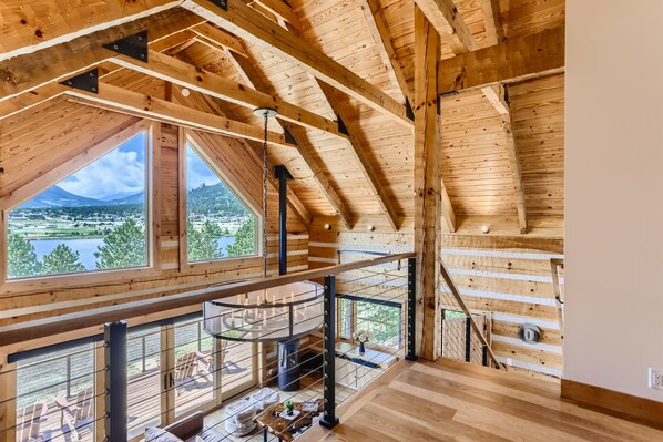 Un intérieur en bois avec un plafond haut, de grandes fenêtres et une vue sur un lac et une ville.