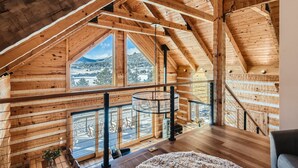 A wooden interior with a high ceiling, large windows, and a spiral staircase. - Lake Front! Mtn/Lake Views,HotTub,Gas FirePit,Walking Trail to town & shopping (Estes Park)