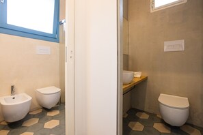 Ein Badezimmer mit einer Bidet-Funktion, Toilette und einem Ablagebereich mit Handtüchern.