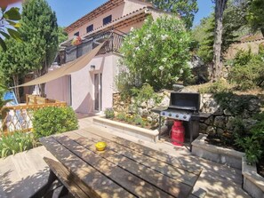 Eine Terrasse mit Grill, einem Tisch und einer gelben Schüssel sowie ein Gebäude mit Balkon.