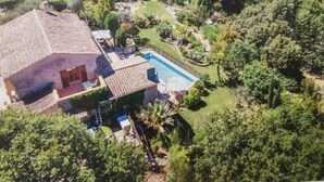 Vista aérea de una casa con piscina rodeada de exuberante vegetación.